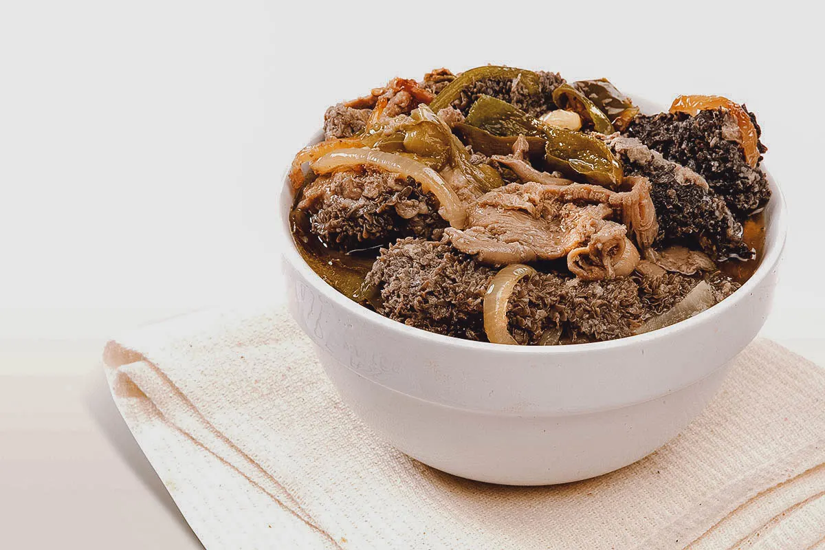 Mala Mogodu — slow-cooked tripe with onions and peppers in a white bowl